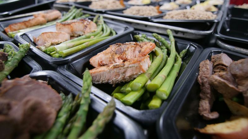 Freshly prepared meals of salmon, steak and asparagus portioned into containers